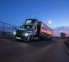 Ein beleuchteter Lkw von Daimler Truck fährt in die anbrechende Dunkelheit auf einem Highway.