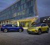 Zwei VW ID.4-Modelle stehen bei Abenddämmerung vor einem Konzerngebäude.