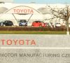Schriftzug "Toyota Motor Manufacturing Czech Republik" mit Werk und Fahrzeugen im Hintergrund.