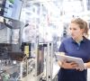 Mitarbeiterin mit Tablet steht an einer Industrieanlage in einem Bosch-Werk