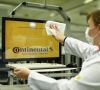 Eine Mitarbeiterin von Continental reinigt einen Bildschirm mit Conti-Logi mit einem Wischtuch.